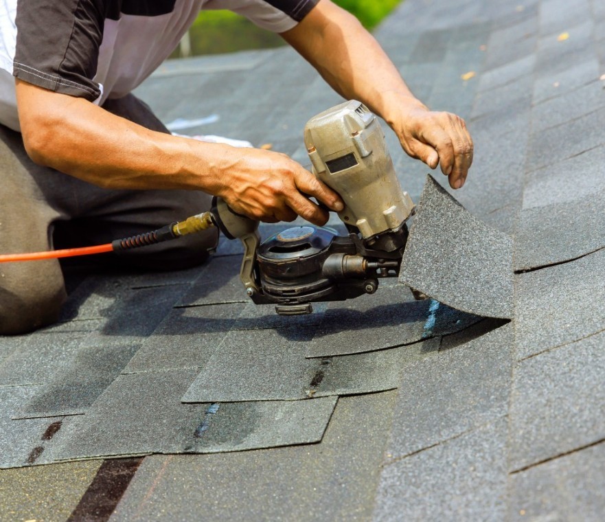 Worker installing shingles with nail gun