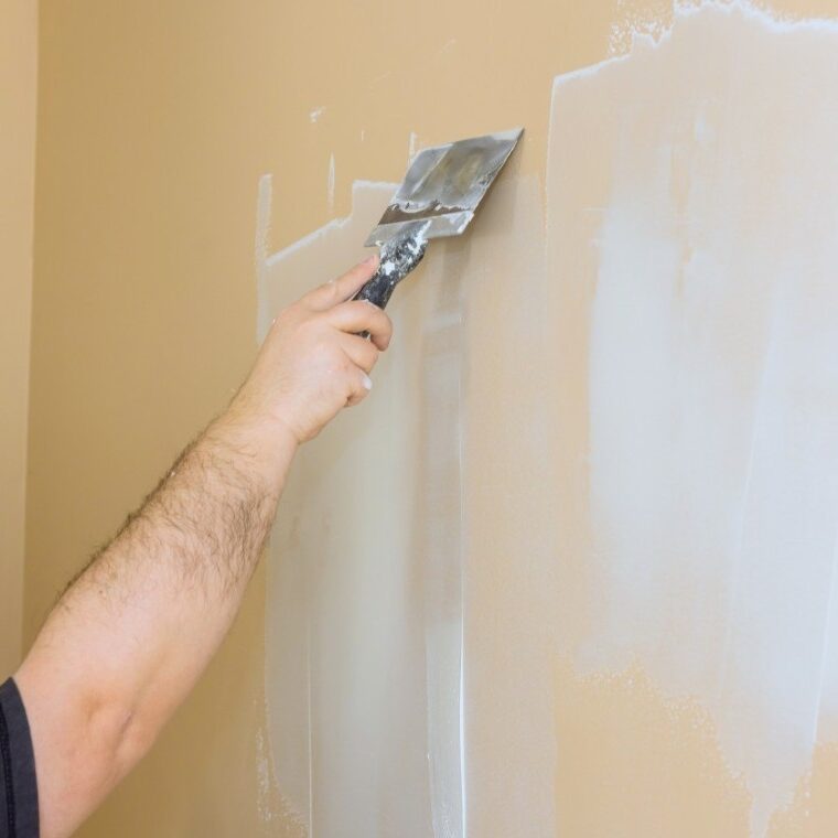 Hand applying plaster to wall